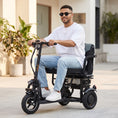 Charger l'image dans la visionneuse de la galerie, Mise en situation du YEYE POP par une personne à mobilité réduite qui utilise la trottinette électrique 3 roues avec siège ergonomique dans ses trajets du quotidien